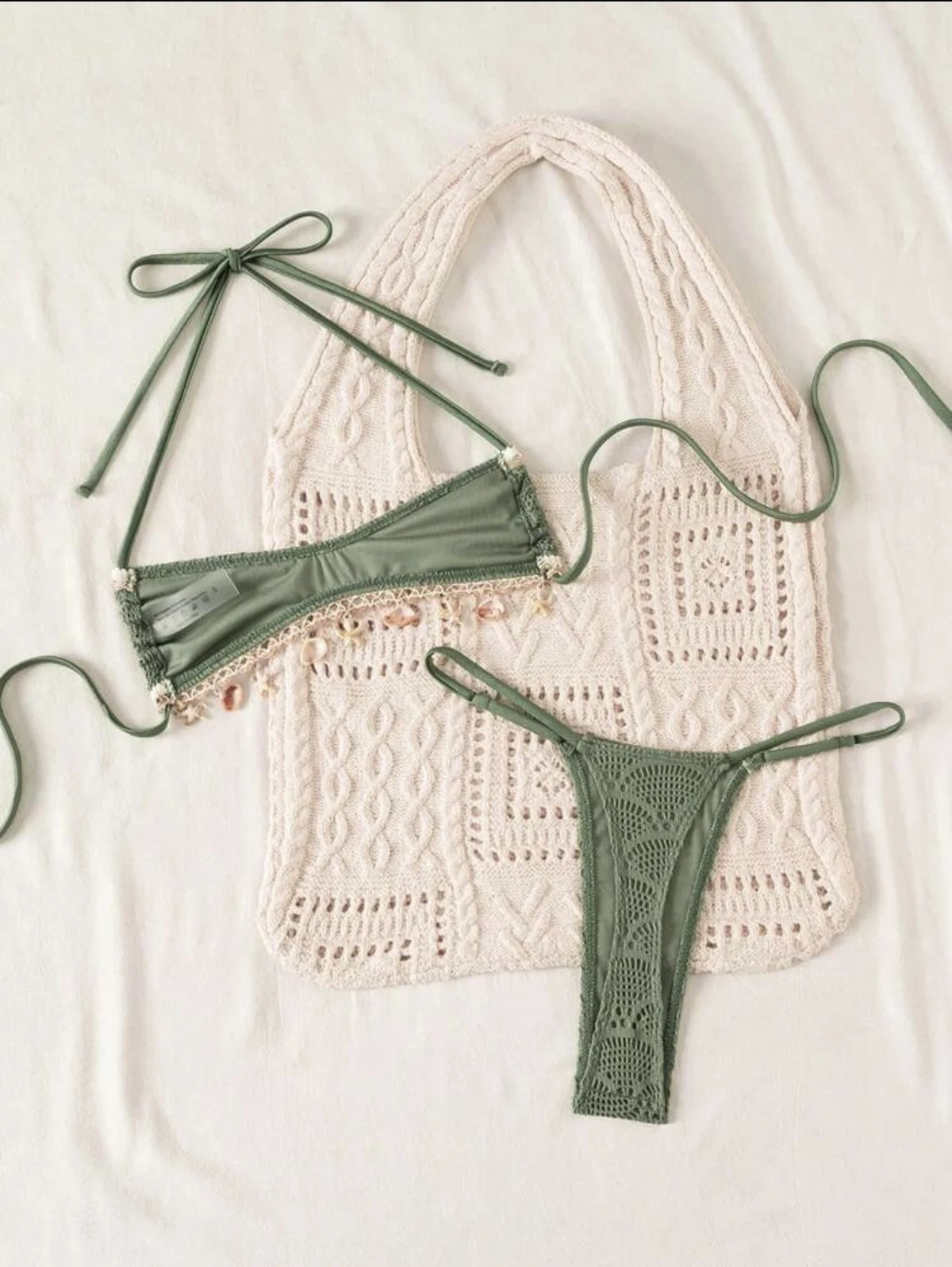 Green bikini with decorative trim photographed flat on a neutral surface