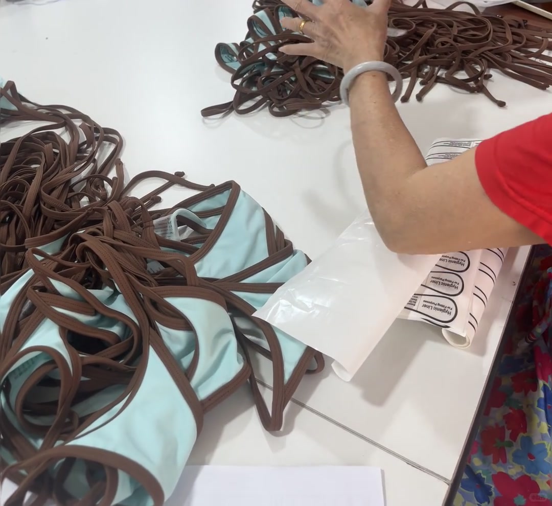 Hands trimming garment straps and arranging components on a table