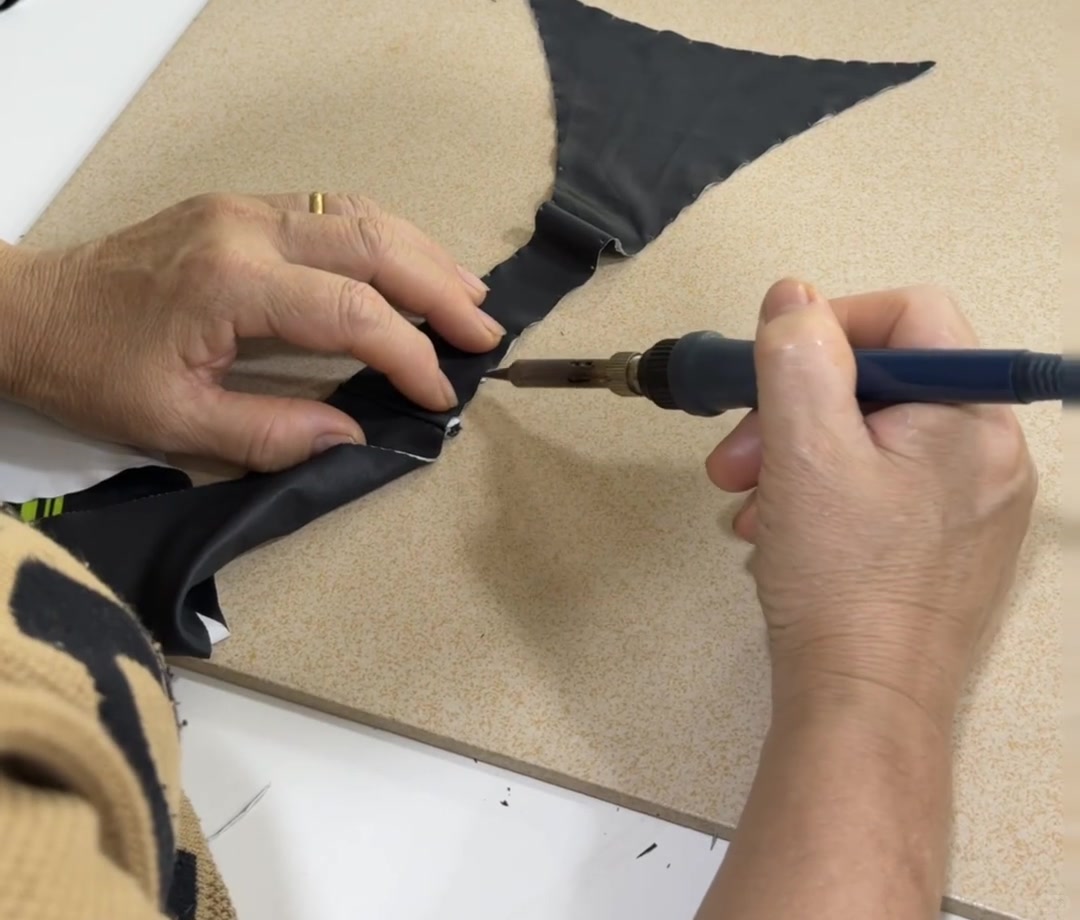 Hands adjusting a dark fabric edge on a worktable