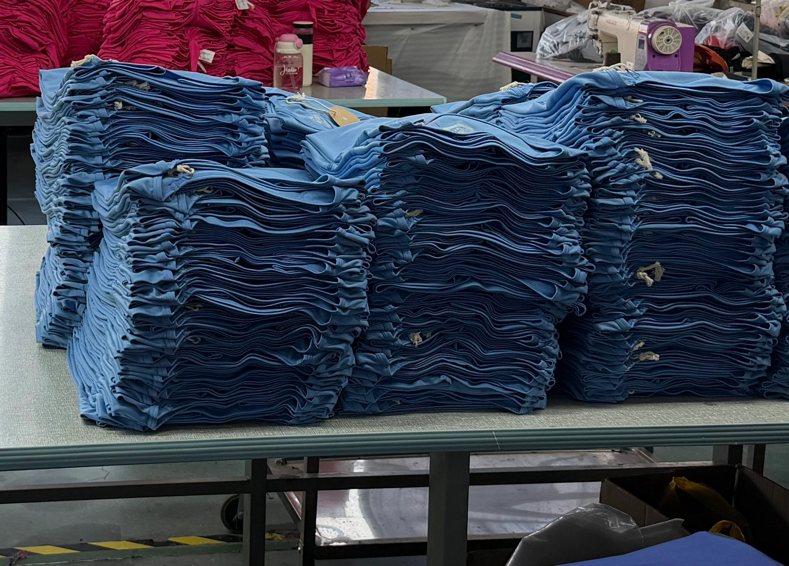 Blue garment components stacked in separate bundles on a worktable