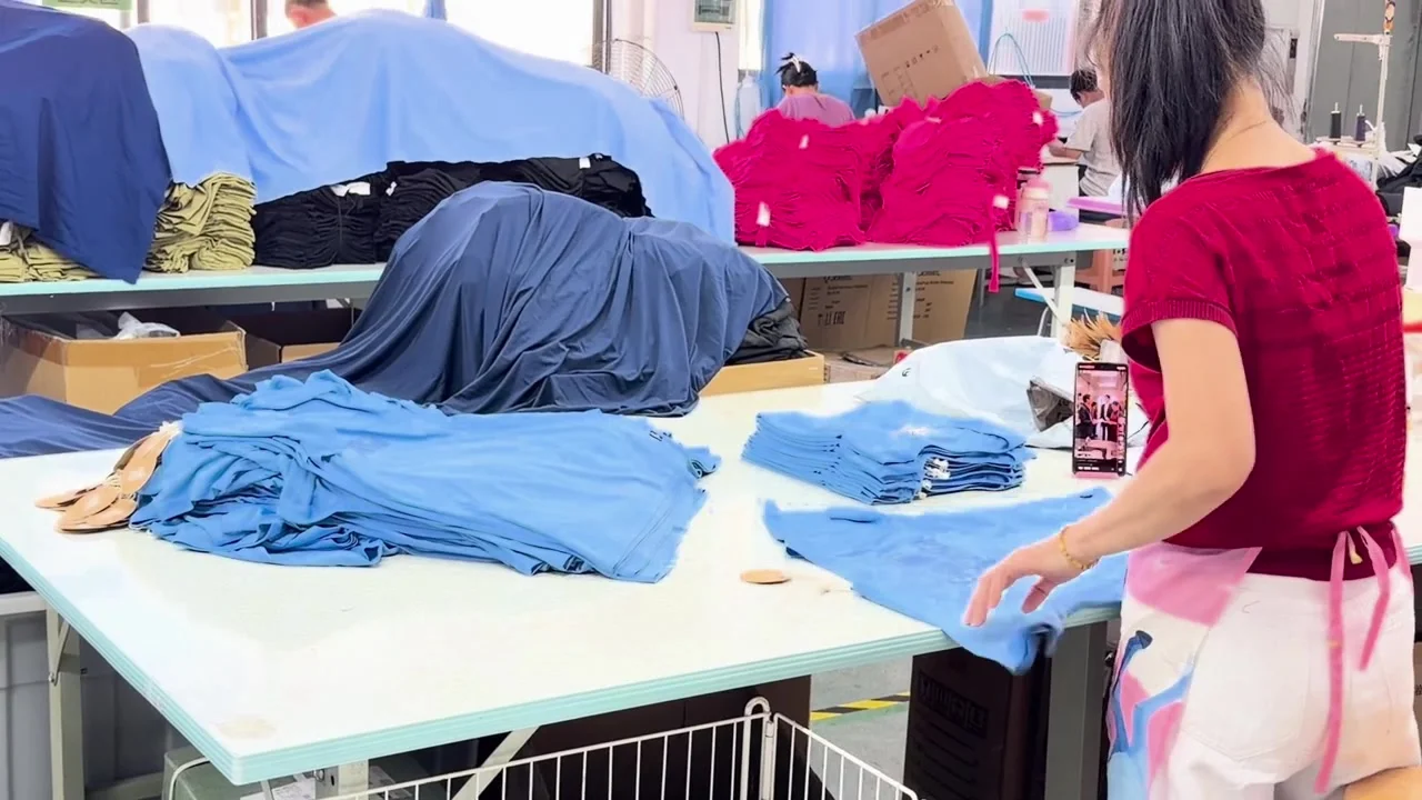 An operator arranging and folding blue garments on a worktable