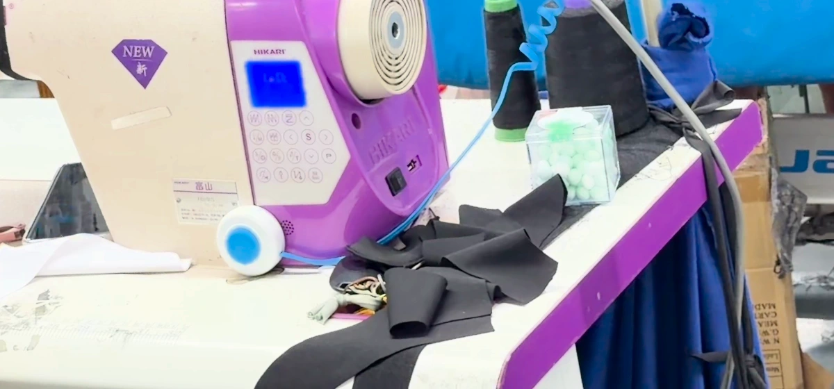 Dark garment components beside a sewing machine, ready for the next assembly operation.