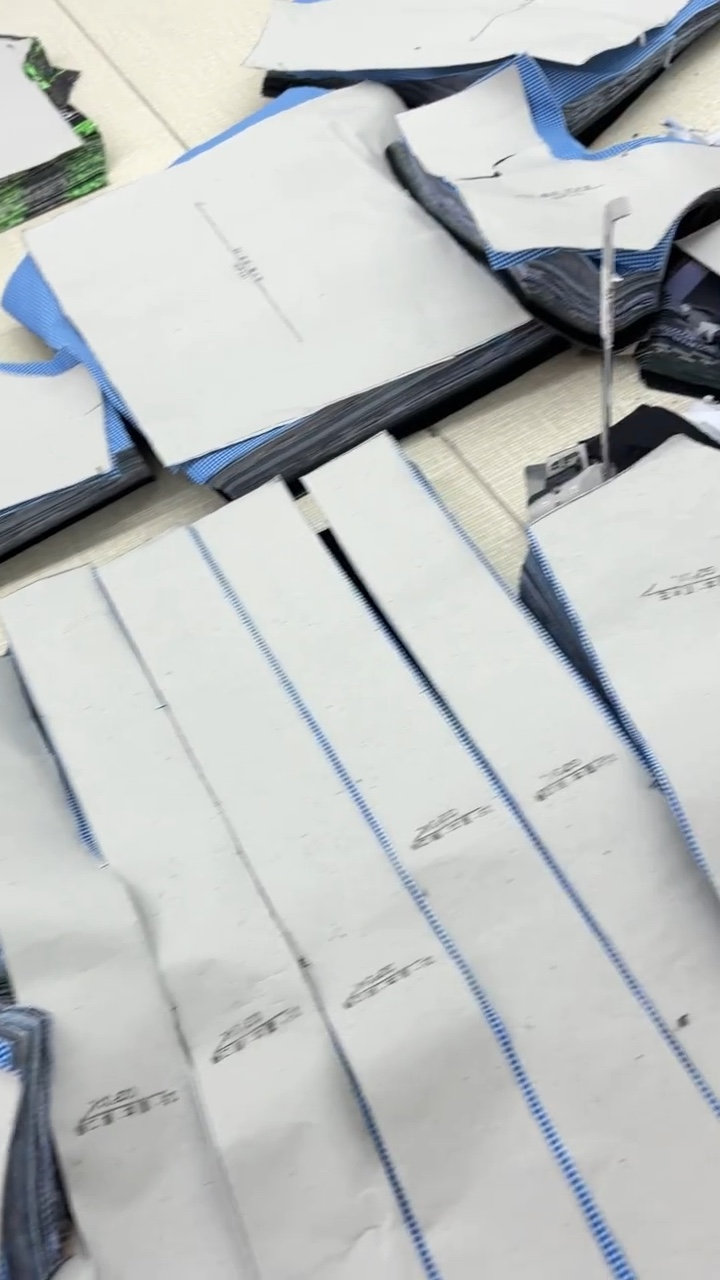 Hands reviewing garment panel details on a worktable