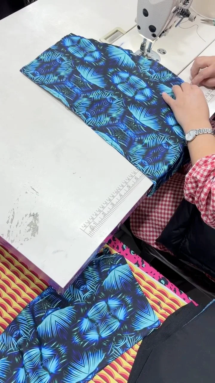 Hands aligning a blue leaf-print panel beside a sewing machine