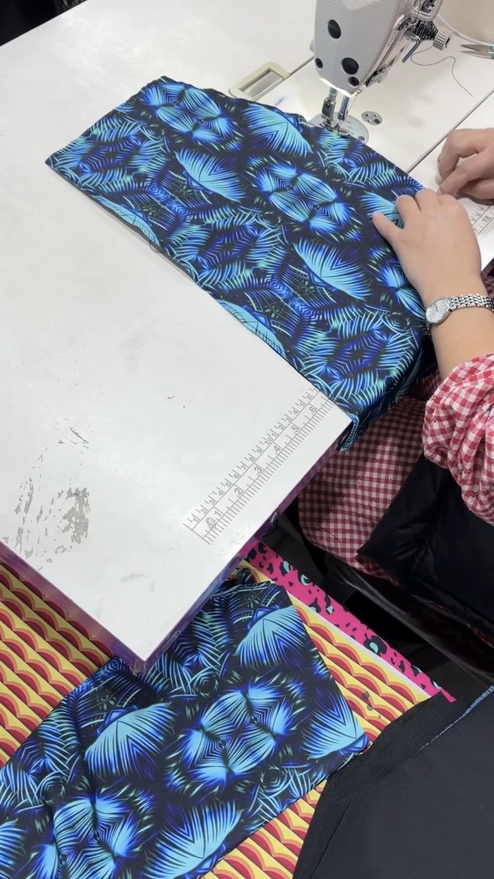 Hands reviewing a printed garment panel at a sewing worktable