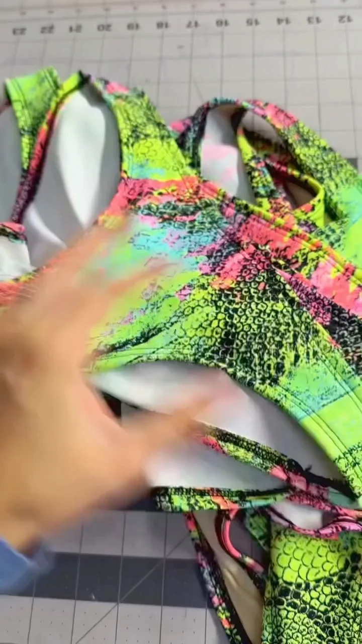 Hands arranging a brightly patterned garment panel on a gridded work surface