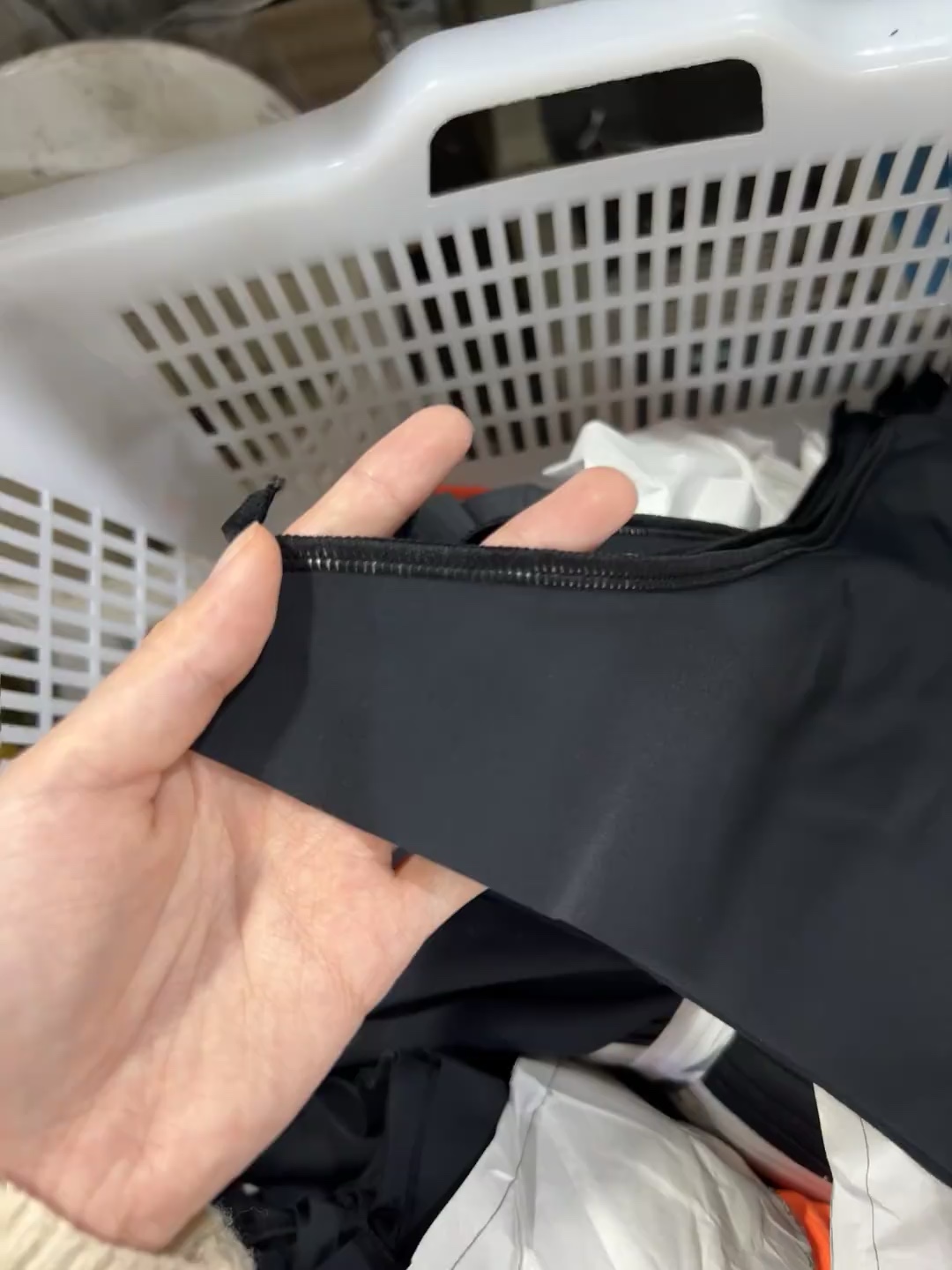 Hands checking the seam and edge finish of a dark garment